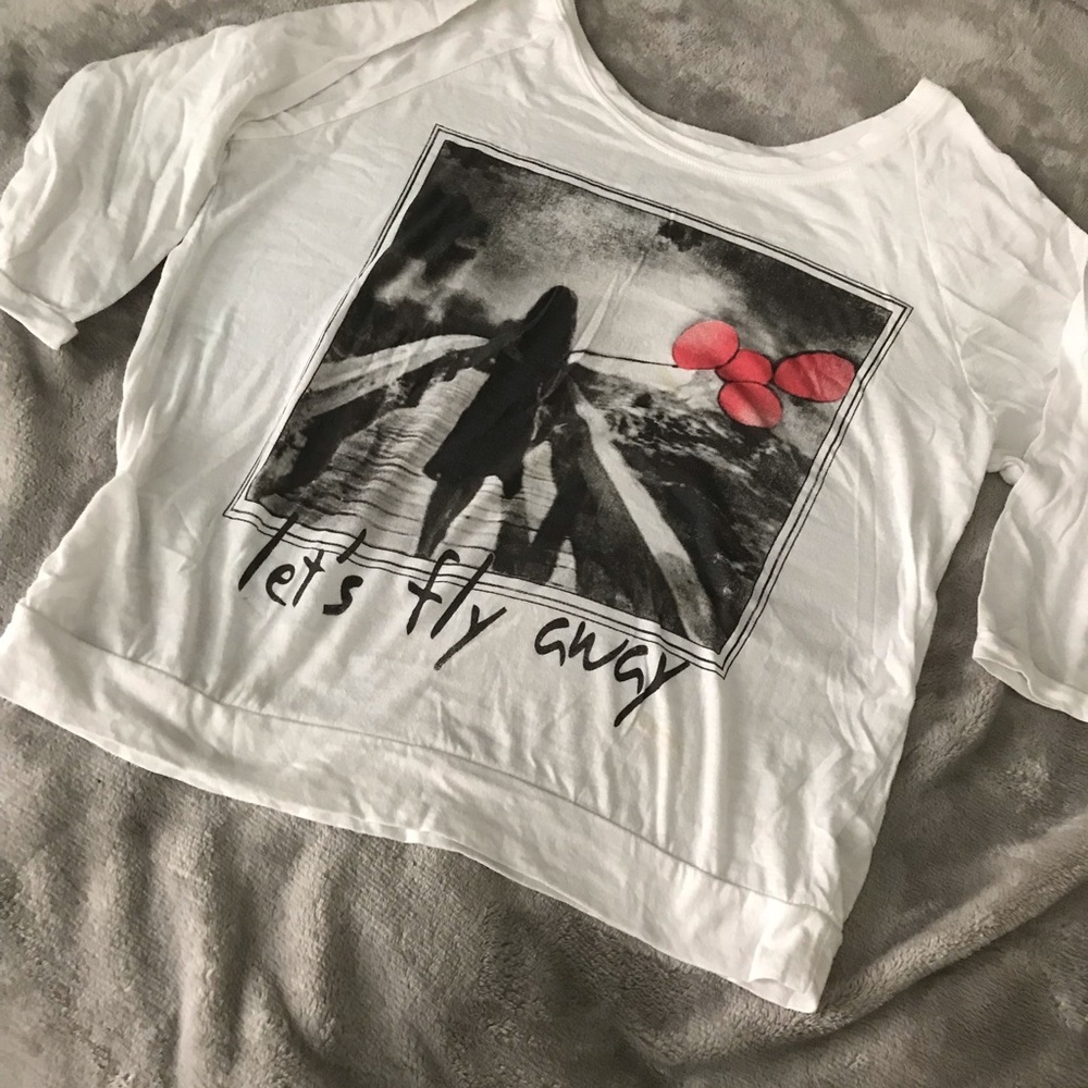 White t-shirt with let’s fly away graphic on front.
